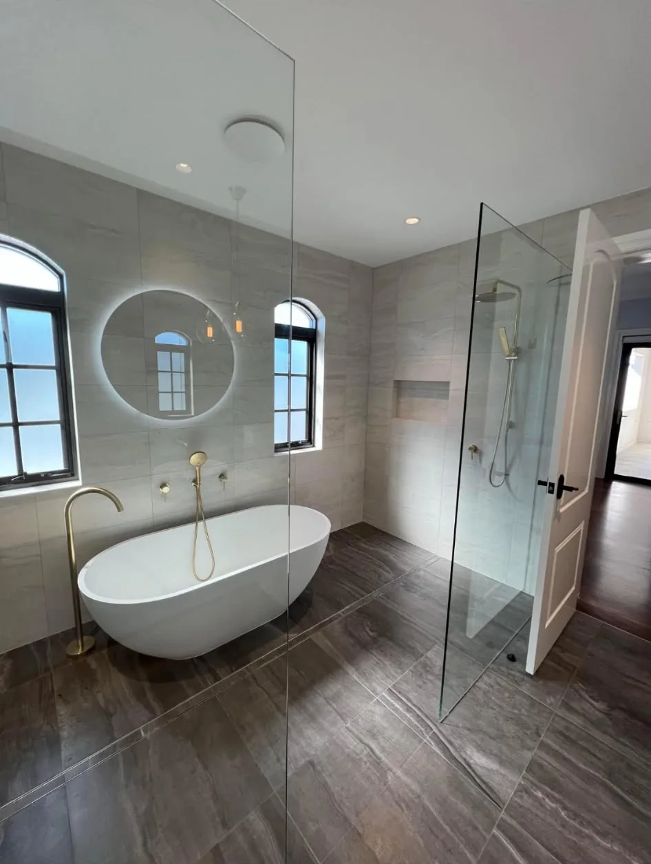 Freestanding bath with brass tapware and backlit mirror