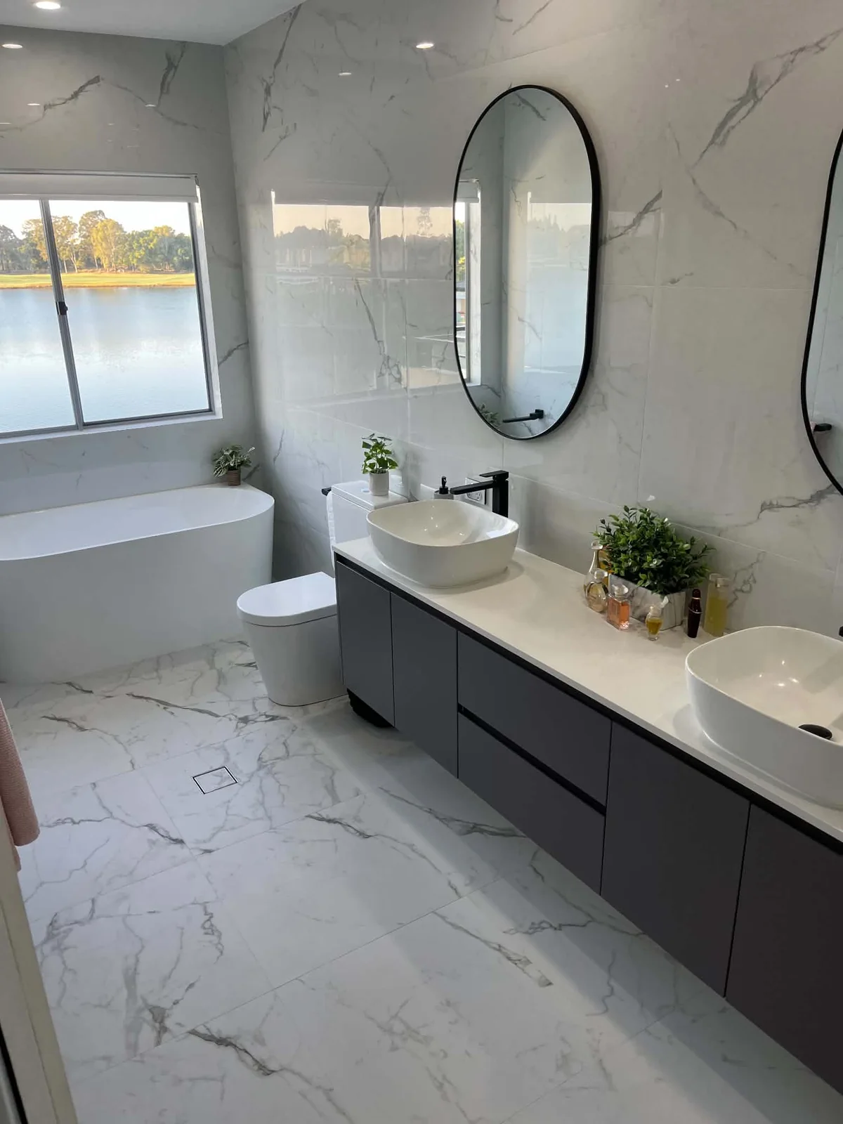 Marble-look bathroom with double vanity and lake view