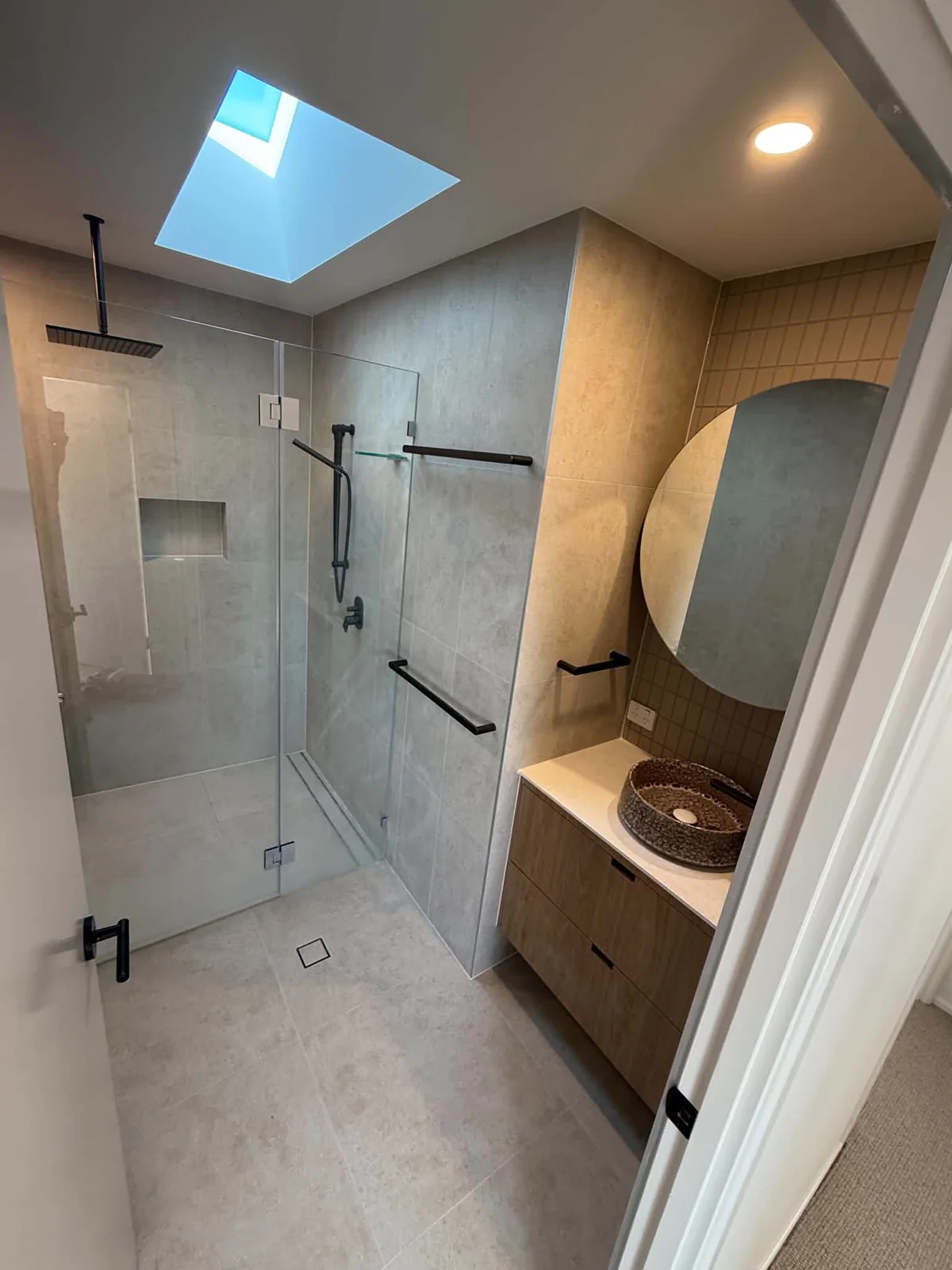 Ensuite with skylight, walk-in shower and finger-tile feature wall