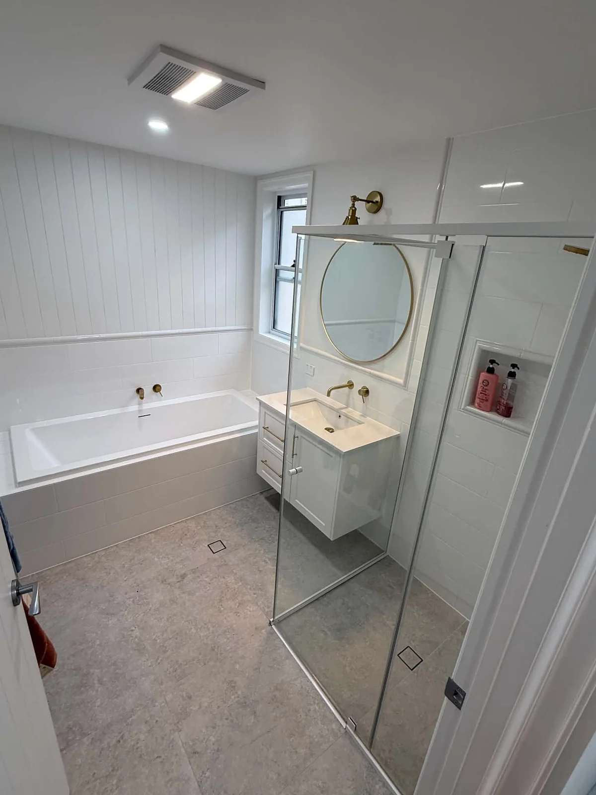 White bathroom with VJ-style wall tiles and brass tapware