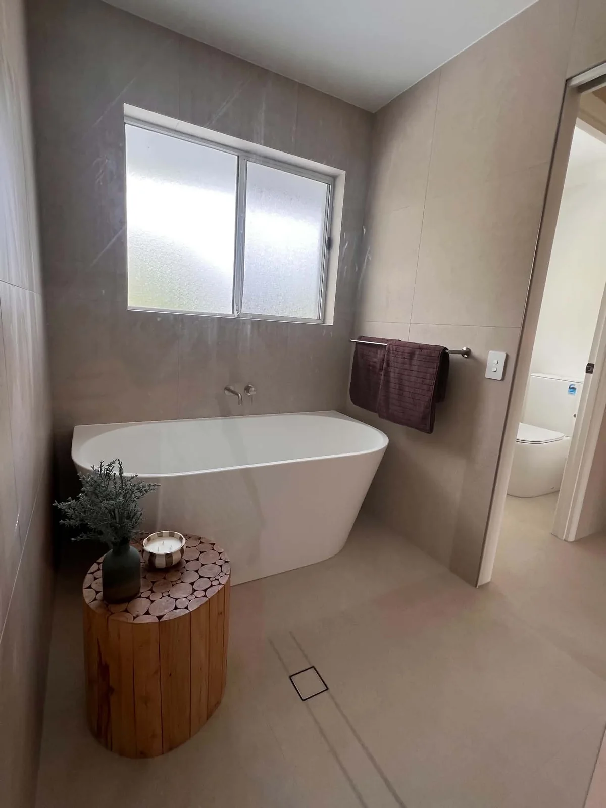Freestanding bath against large-format grey tiles